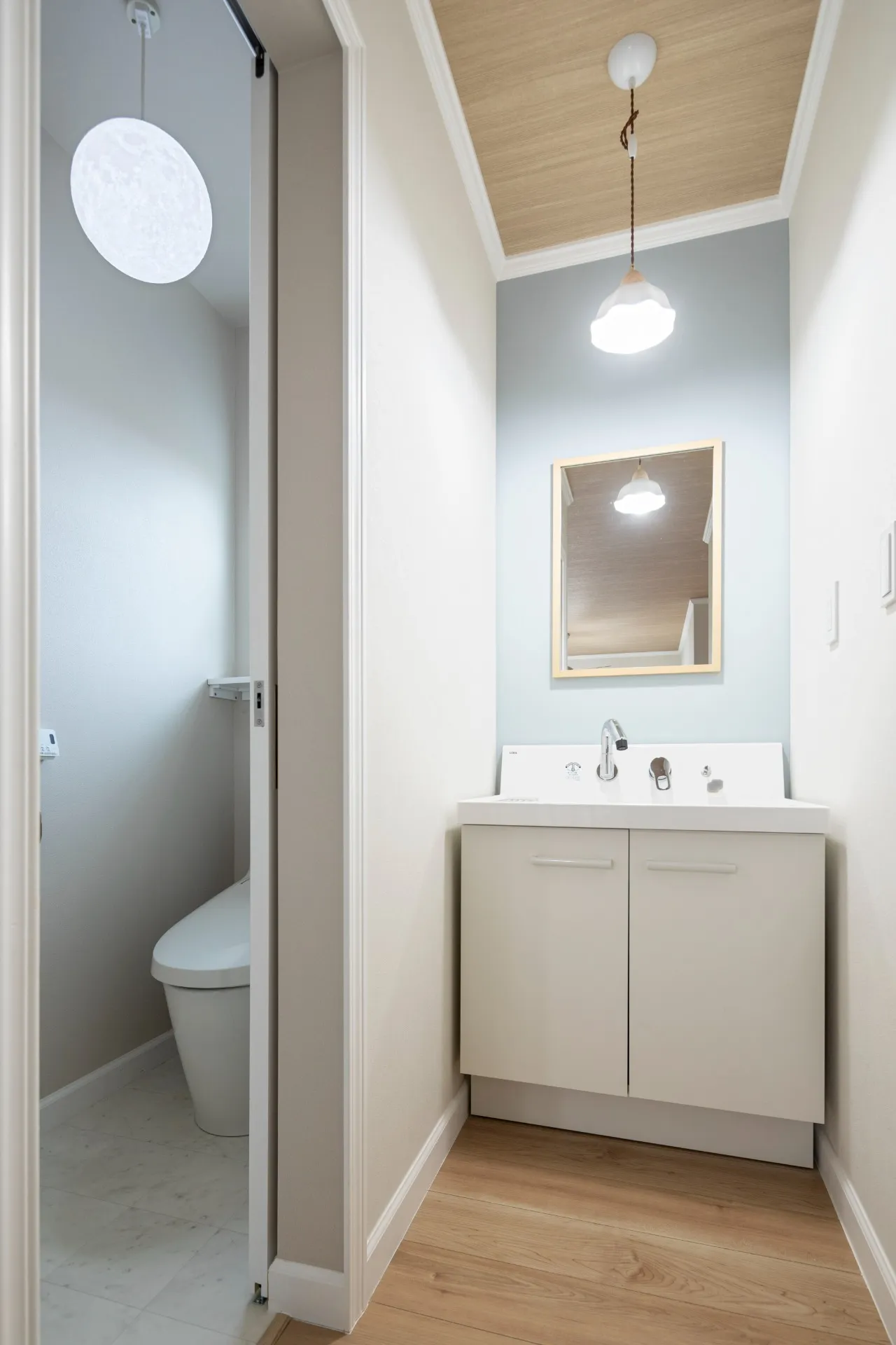 こちらはシンボルカラーとした淡いブルーのアクセントウォールが印象的な洗面＆トイレ。バスルームやランドリーなどの水まわりは１階に集中し、洗濯物は基本室内干し。そのうえファミリークロゼットに近接させることで「洗濯動線」は大幅に向上。