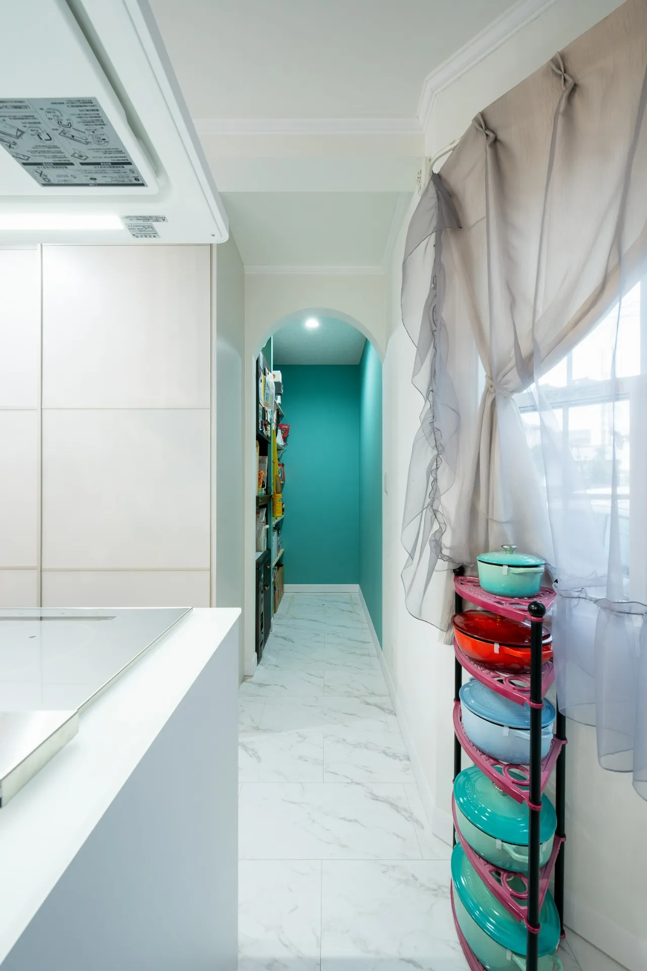 収納のほかにパントリーも配置することで、収納力はさらにアップ。アールをつけた垂れ壁にターコイズブルーのアクセントクロスがおしゃれ。右に見える出窓部分も猫たちのお気に入りの場所。