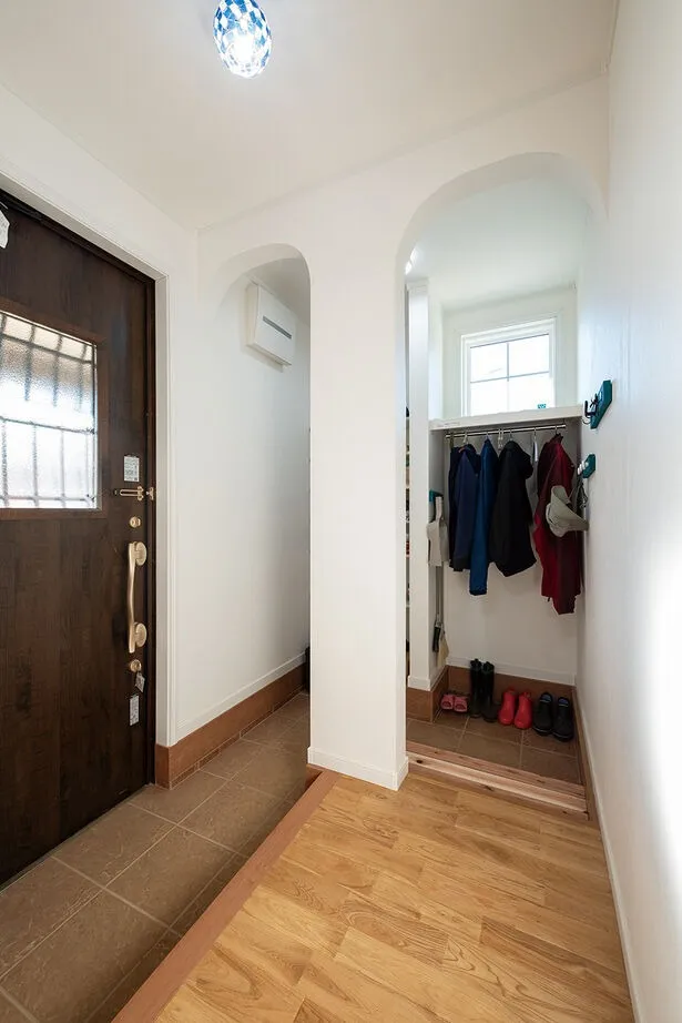 ２つのアーチ壁が印象的な玄関収納。「新居でDIYをする予定があったので、靴以外にもモノづくりの道具などを収納できるスペースが欲しいと希望しました」とお施主様。また、暗くなりがちな玄関に光を取り込むため、扉や収納内に採光窓を設けています。