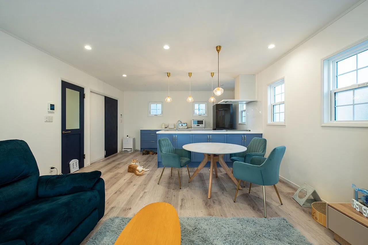 外観と同じペールブルーのオーダーメイドキッチンが印象的なLDK。建具や家具も寒色系で揃え、インテリアに統一感を持たせている。同社標準仕様の白い窓枠やSさんが選んだペンダントライトも空間に調和し、輸入住宅らしい洗練された雰囲気を引き立てている