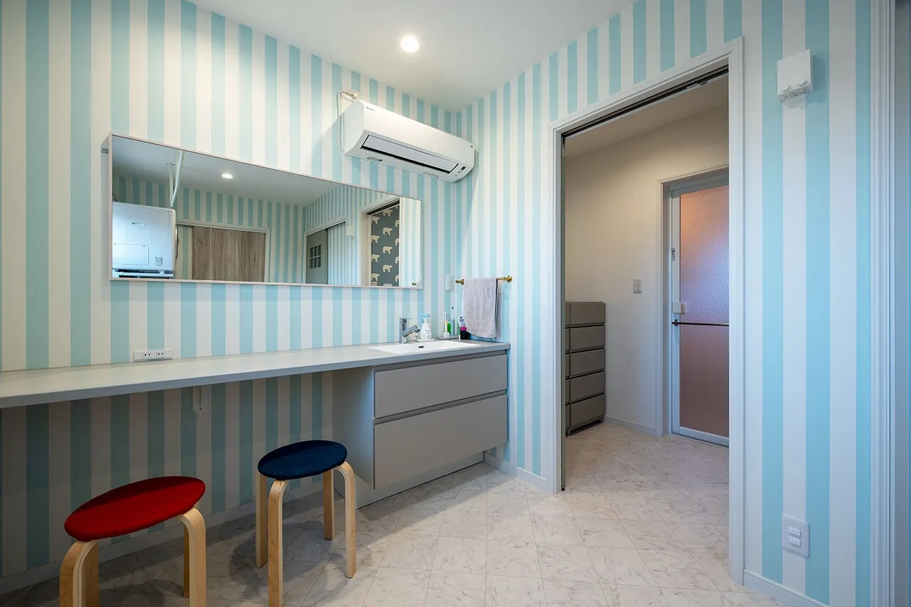 2階の洗面室兼ランドリールームは、ストライプのクロスで明るく爽やかな印象に。脱衣室は扉で仕切れるようになっているので、家族が入浴している時も気兼ねなく使える。「カウンター付きの洗面台が広くて使いやすく、夫婦並んで朝の支度ができるので便利です」（Sさん）